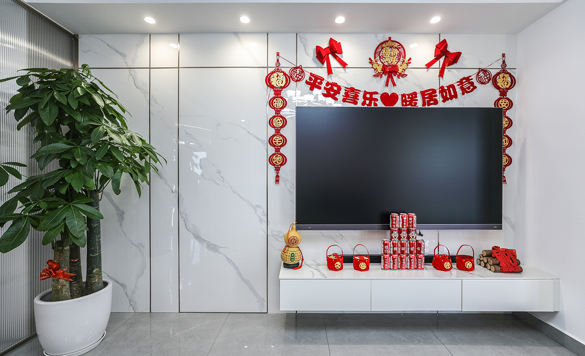 亮光石紋竹木纖維板和極窄線條將房門和背景完美集合，電視柜左邊的裝飾盆景作襯托，巖板臺(tái)面電視柜也很大氣，讓空間不但時(shí)尚而且清爽。